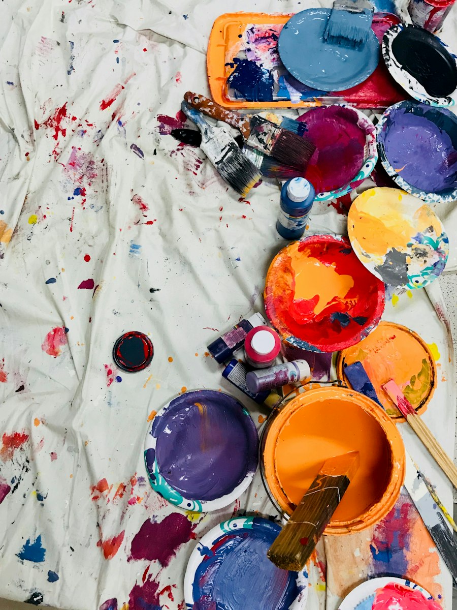 Pots de peinture de toutes les couleurs sur une toile tachée, vue de dessus