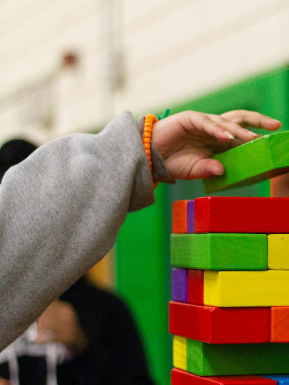 Une main d’enfant empile des blocs de bois colorés