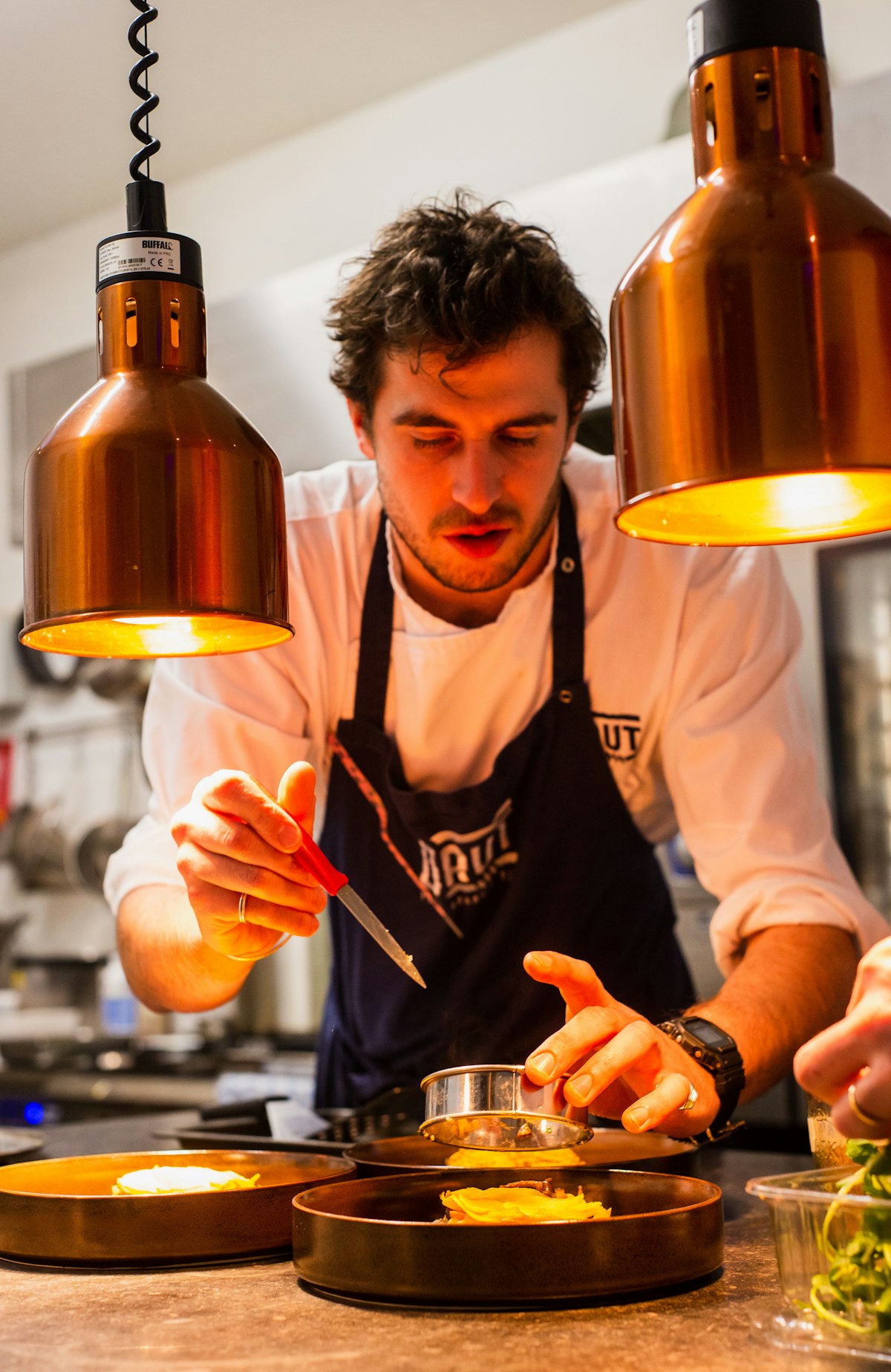 Le chef dresse une assiette sous les lampes chauffantes