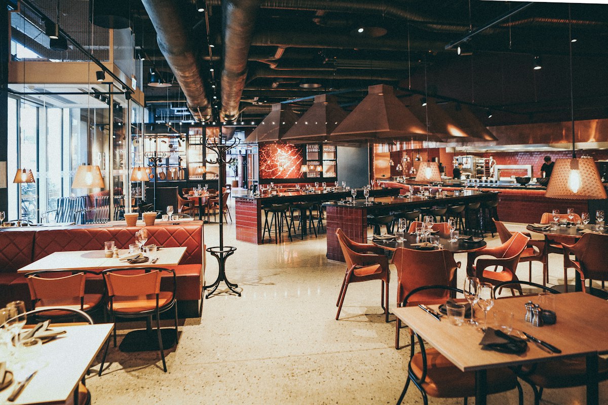 La salle de la brasserie, banquettes rouges et tables dressées