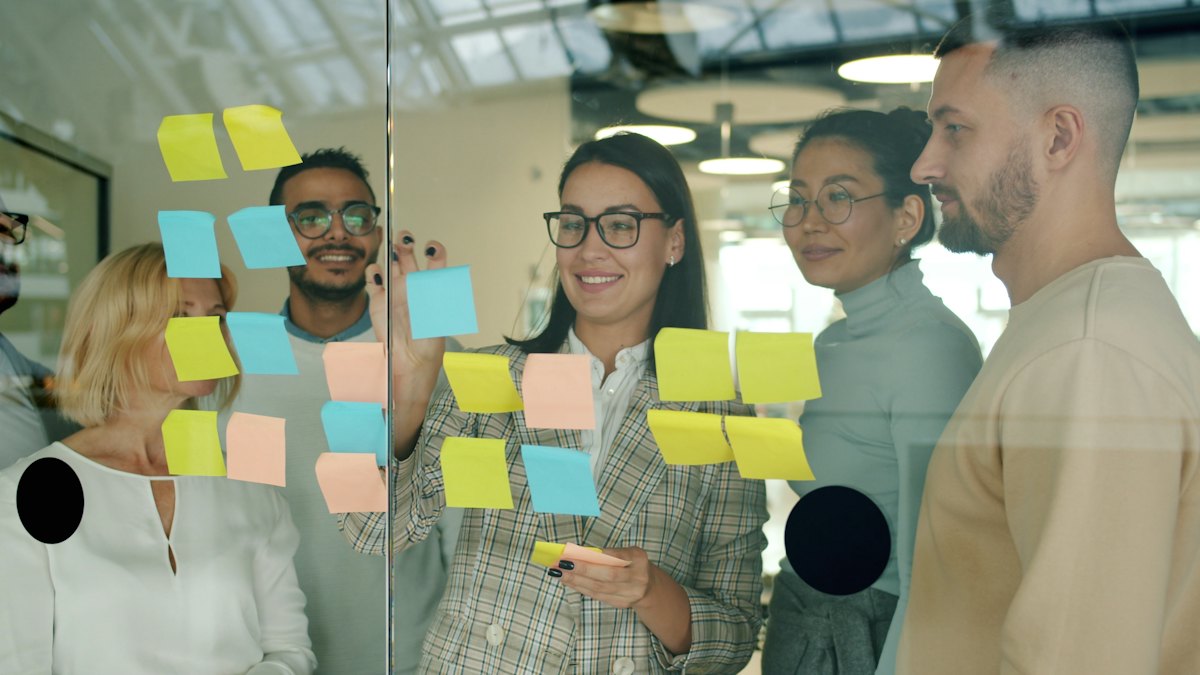 Atelier collaboratif autour de notes adhésives sur une paroi vitrée